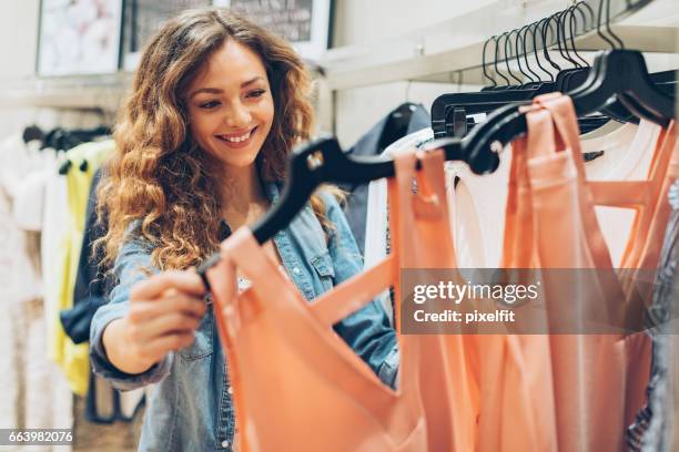 jeune femme passant en revue dans le magasin de mode - clothing photos et images de collection