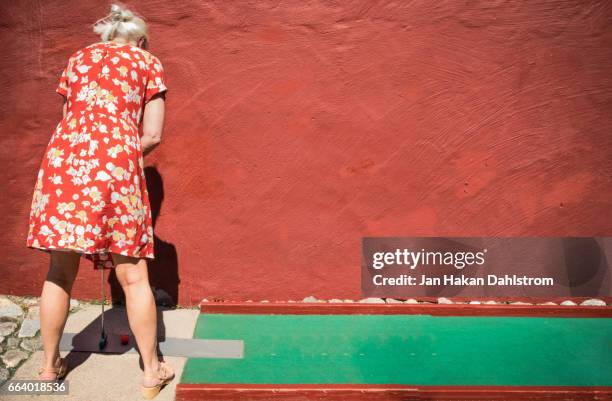 woman playing miniature golf - minigolf stockfoto's en -beelden