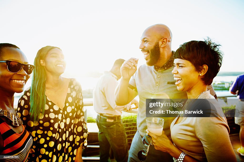 Laughing couple sharing drinks with friends