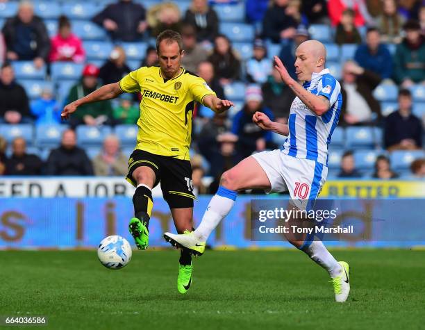Aaron Mooy of Huddersfield Town is tackled by Luke Varney of Burton Albion during the Sky Bet Championship match between Huddersfield Town and Burton...