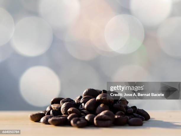 heap of coffee beans toasted on a table of wood illuminated by the light of the sun - semilla photos et images de collection