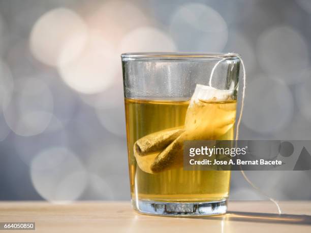 glass cup on a table to prepare an infusion of grasses of tea (tea bag ),  illuminated by the light of the sun - chamomile tea stock pictures, royalty-free photos & images