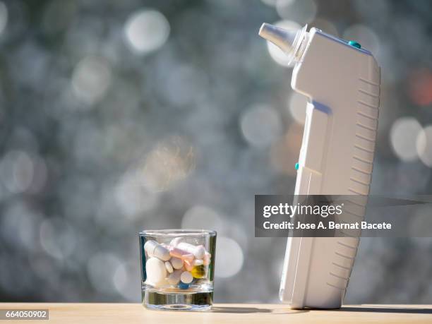 digital thermometer of ear,  and a dose of medication with pills and pills - herramientas profesionales stockfoto's en -beelden