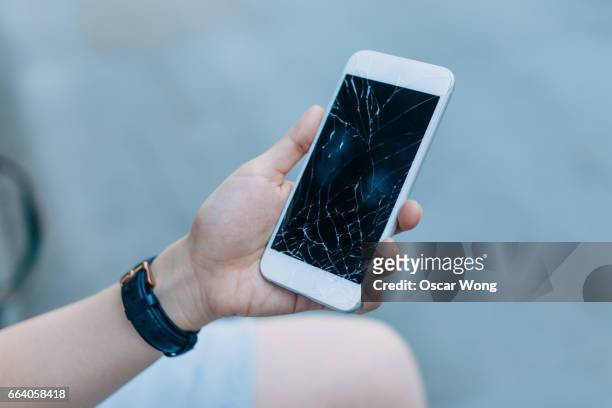 woman with shattered cell phone - damaged stock-fotos und bilder