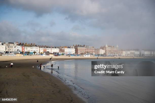 People walk on the beach as sea mist rolls in from the sea at Weymouth as the resort prepares for the start of the holiday season on April 3, 2017 in...