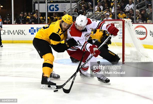 Lee Stempniak of the Carolina Hurricanes fights for the puck with Bryan Rust of the Pittsburgh Penguins at PPG PAINTS Arena on April 2, 2017 in...