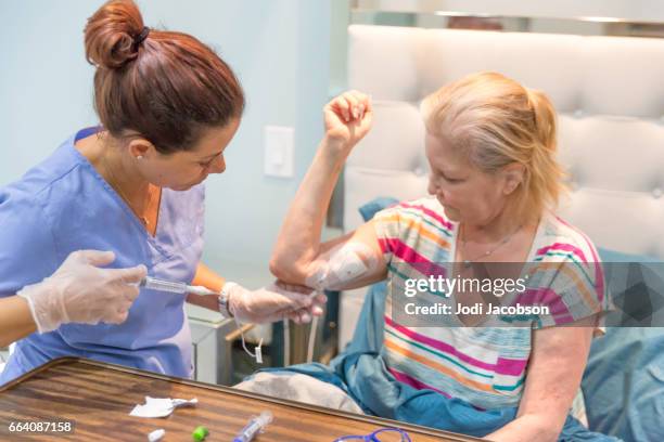 home healthcare nurse flushing out the picc line of her female patient - catheter stock pictures, royalty-free photos & images