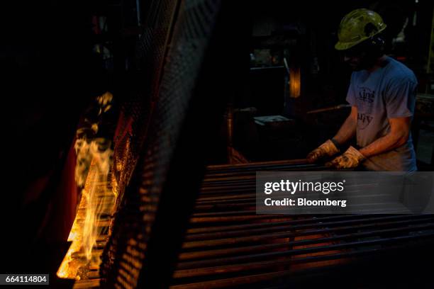 An employee places steel rods in a furnace as tools are forged at the Vaughan & Bushnell Manufacturing Co. Facility in Bushnell, Illinois, U.S., on...