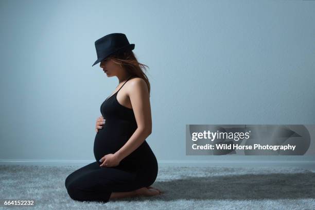 pregnant woman in black dress kneel on the carpet - woman kneeling stockfoto's en -beelden