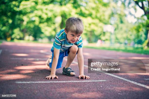 little boy preparing for run on the running track - boy running track stock pictures, royalty-free photos & images