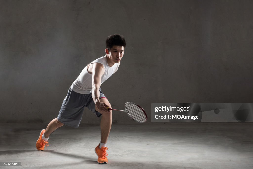 An adult man playing badminton