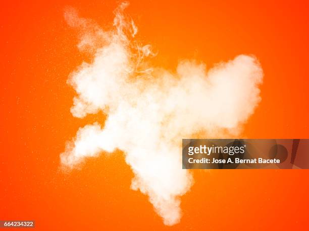 explosion of a cloud of powder of particles of  color white on a orange background - etéreo stockfoto's en -beelden