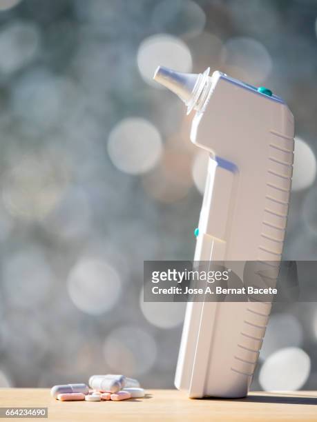 digital thermometer of ear,  and a dose of medication with pills and pills - herramientas profesionales stockfoto's en -beelden