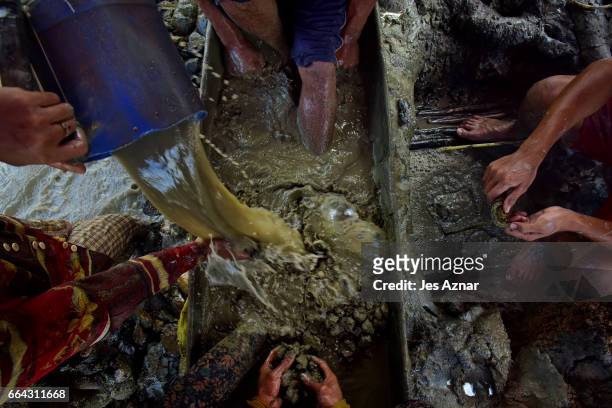 The Balderosdasco family manually dissolving mud with their feet and hands to look for gold on March 22, 2017 in Paracale, Philippines. Apart from...