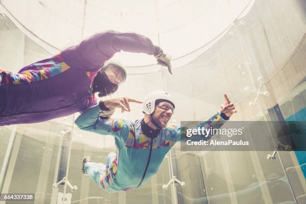 binnenshuis parachutespringen - instructeur onderwijzen hoe te vliegen - freefall simulatie - indoor skydive stockfoto's en -beelden