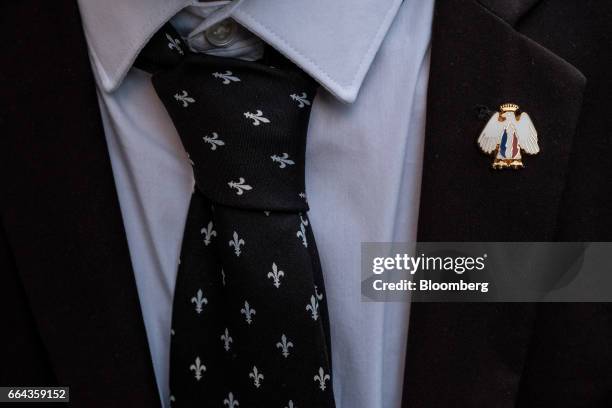 An enamel pin badge of the French National Front political party sits on the lapel of a supporters suit during a local campaign event in Thuir,...