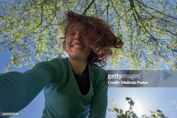 woman taking a self portrait by leaning over camera - inclinar se pose imagens e fotografias de stock