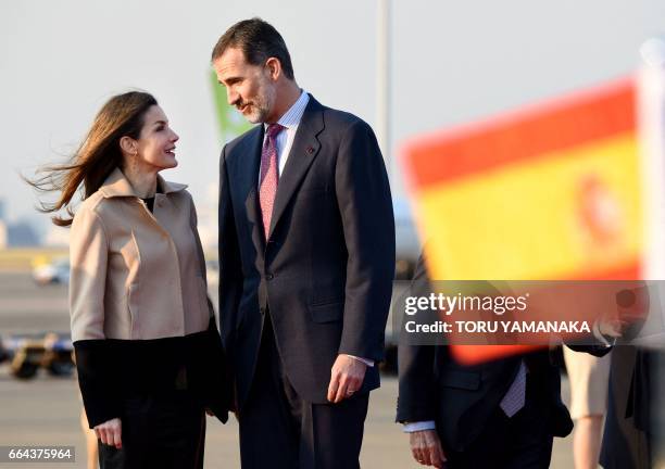 Spanish King Felipe VI and Queen Letizia stand beside a Spanish national flag upon their arrival at Haneda Airport in Tokyo on April 4, 2017. The...