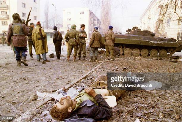 Chechen soldiers mill around the body of a dead Russian serviceman outside of the presidential palace in the center of Grozny in Jan. 1995 during...