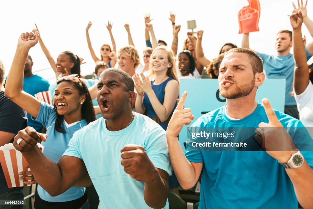 Crowd of fans cheering from stadium bleachers