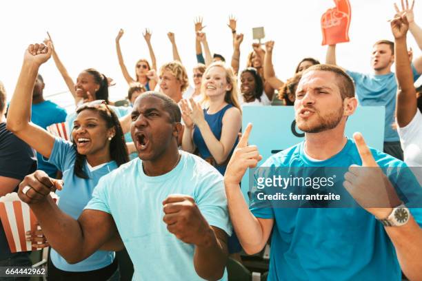 crowd of fans cheering from stadium bleachers - crowd cheering stock pictures, royalty-free photos & images
