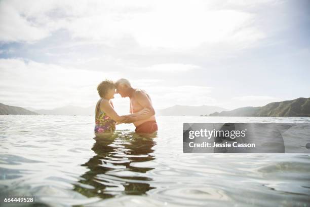 older couple in sea at sunset - senior couple stock pictures, royalty-free photos & images