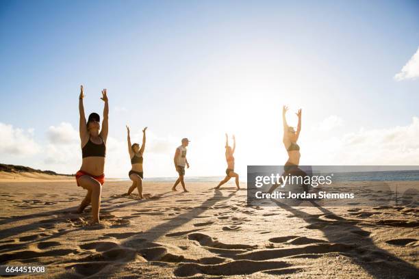 friends doing yoga in the sand. - yoga retreat stock pictures, royalty-free photos & images