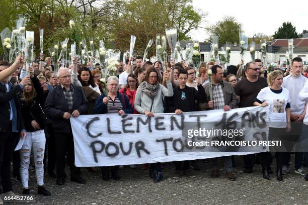 People and relatives of Clement B, a 16 years old teenager found dead in a pond in Ham, hold white roses and banner reading "Clement 16 years old,...