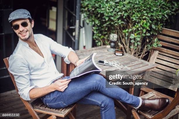 man reading a magazine in cafe - legs crossed at knee stock pictures, royalty-free photos & images