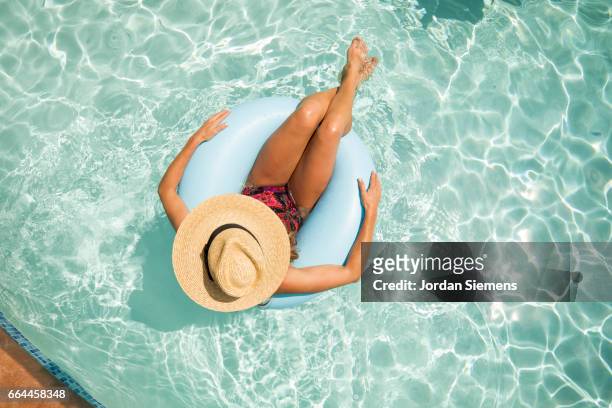 a woman floating in a pool. - zwemband stockfoto's en -beelden