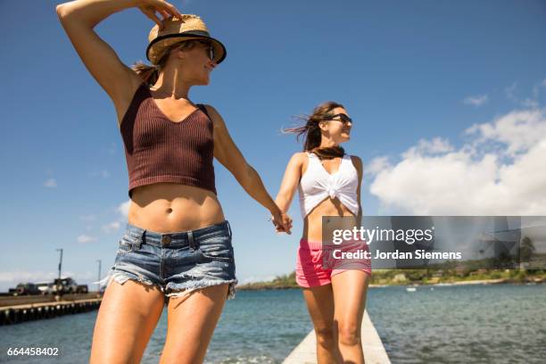 two females holding hands - bauchfreies oberteil stock-fotos und bilder