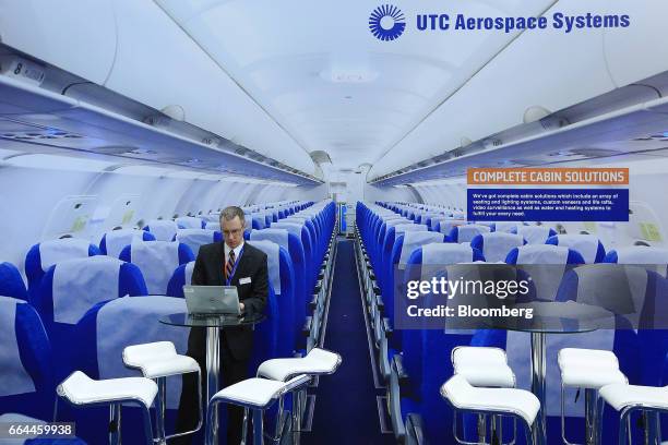 An attendee uses a laptop computer in front of a large photograph of a passenger aircraft interior in the UTC Aerospace Systems pavilion at the 2017...