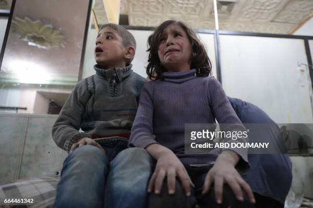 Syrian children wait to receive treatment at a makeshift clinic following reported air strikes by government forces in the rebel-held town of Douma,...