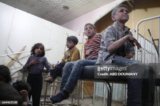 Syrian children wait to receive treatment at a makeshift clinic following reported air strikes by government forces in the rebel-held town of Douma,...