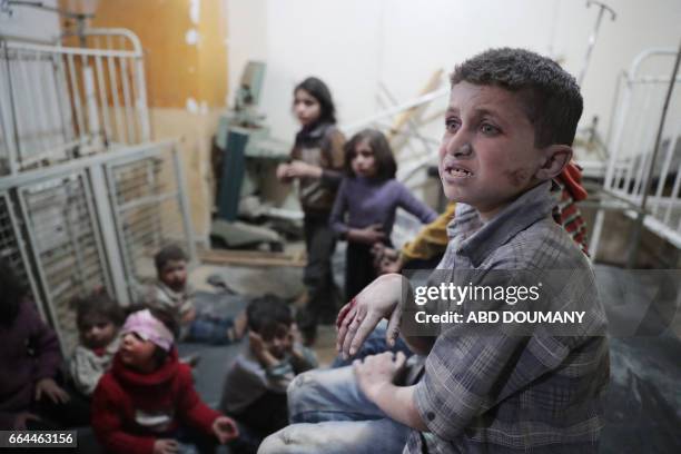 Syrian children wait to receive treatment at a makeshift clinic following reported air strikes by government forces in the rebel-held town of Douma,...