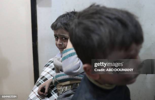 Syrian children wait to receive treatment at a makeshift clinic following reported air strikes by government forces in the rebel-held town of Douma,...