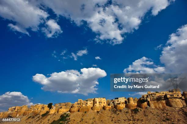 fluffy clouds dot a beautiful blue sky over jaisalmer fort, jaisalmer, rajasthan, india - mittag stock-fotos und bilder