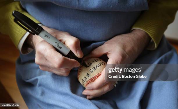 Robert Megerdichian writes his information on an old baseball, which he will distribute as a business card, in his Cambridge, MA home on Mar. 28,...