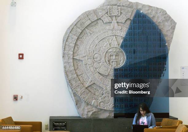 An employee works in front of a sculpture displaying an Aztec calendar in the lobby of the Intel Corp. Design center in Guadalajara, Mexico, on...