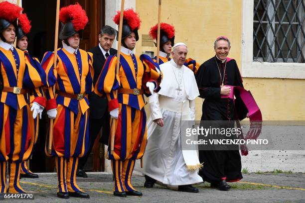 Pope Francis, flanked by the prefect of the papal household Georg Gaenswein walks past Swiss Guards on is way to a private audience with Britain's...