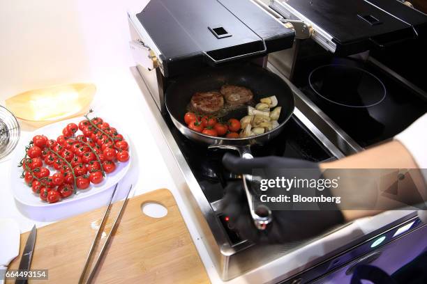 An attendee uses a frying pan during a demonstration to show the operation of a flight safe cooking system by Lufthansa Technik AG at the Aircraft...