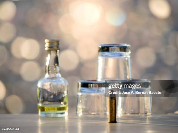 glass of crystal of chupito empty of an alcoholic drink and a bottle of liquor of mini bar , illuminated by the light of the sun - bebida stockfoto's en -beelden