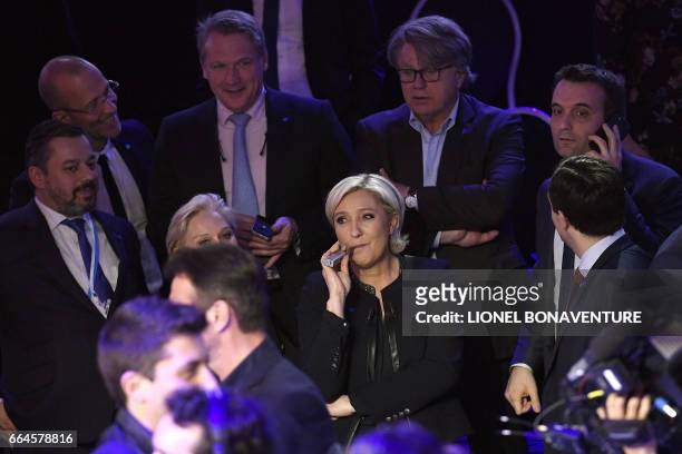 French presidential election candidate for the far-right Front National party Marine Le Pen smokes an electronic cigarette, flanked by French...