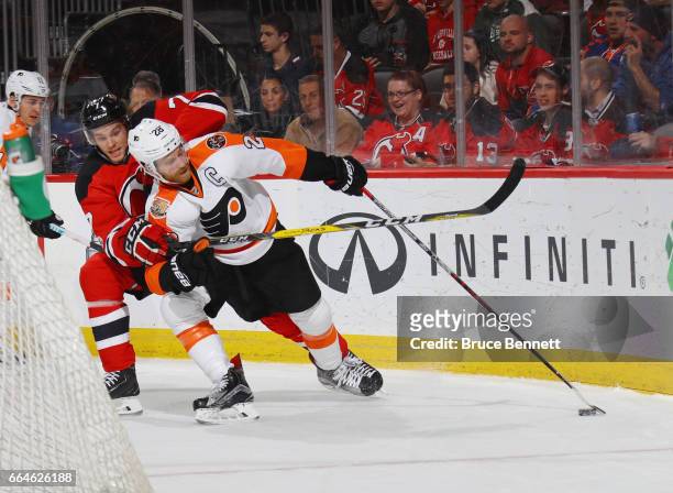 Jon Merrill of the New Jersey Devils holds onto Claude Giroux of the Philadelphia Flyers during the first period at the Prudential Center on April 4,...