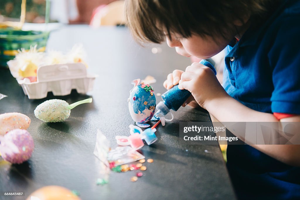 A child decorating eggs at Easter with glitter, glue and paint.