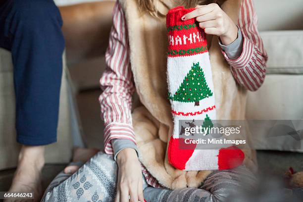 two people unwrapping christmas stocking presents on christmas morning. - christmas stockings stock-fotos und bilder