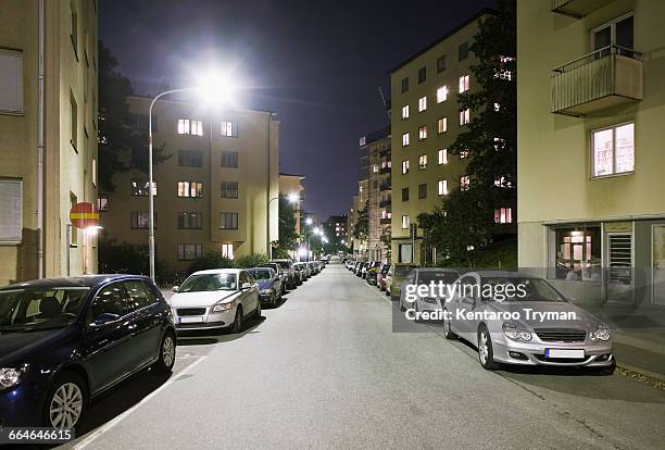 cars parked on street amidst buildings at night - stockholm park stock pictures, royalty-free photos & images