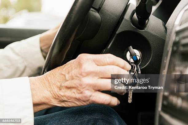 cropped image of senior woman putting car key in ignition lock - car keys hand stockfoto's en -beelden