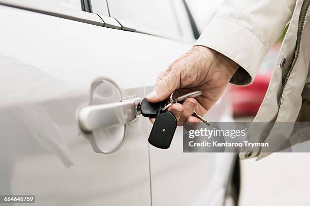 cropped image of senior womans hand unlocking car door - car keys hand ストックフォトと画像