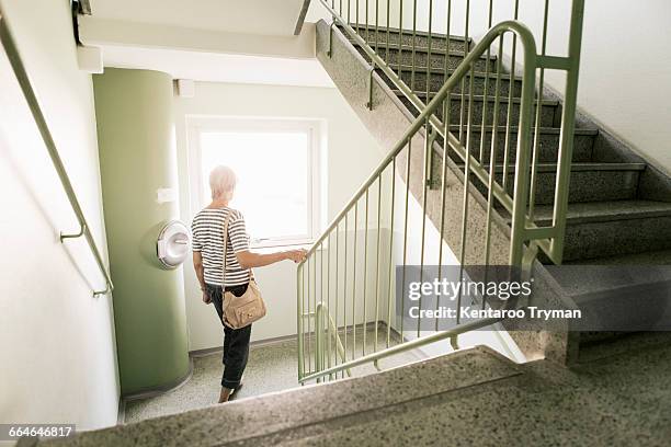rear view of woman walking down on staircase in apartment building - apartment exterior ストックフォトと画像